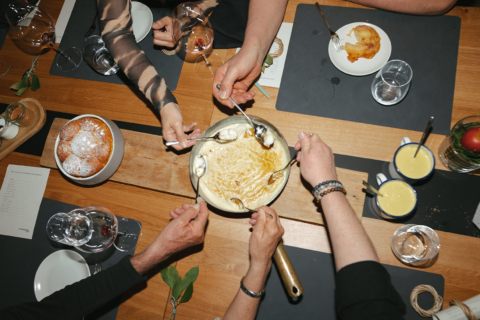 Mehrere Gäste teilen sich am Community Table ein Dessert und genießen gemeinsam den Moment