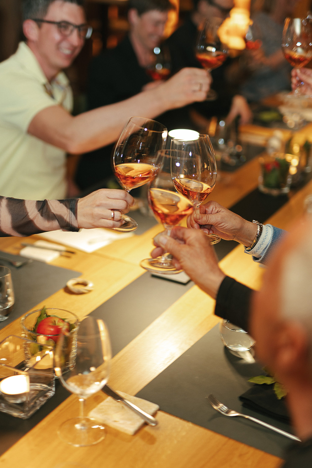 Gäste stoßen am Community Table mit Roséwein an und feiern gemeinsam einen genussvollen Abend
