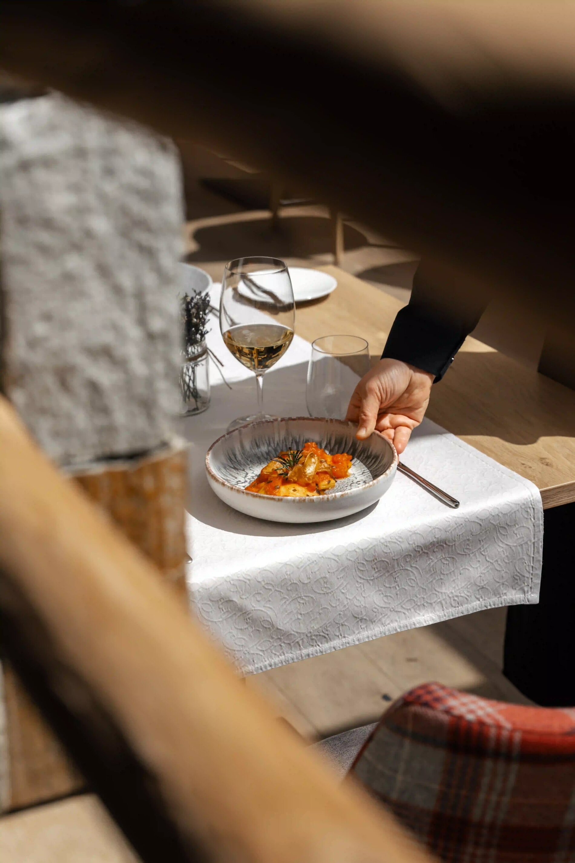 Fein angerichtetes Gericht wird im Cyprianerhof serviert, eleganter Tisch mit Weißwein und alpinem Ambiente