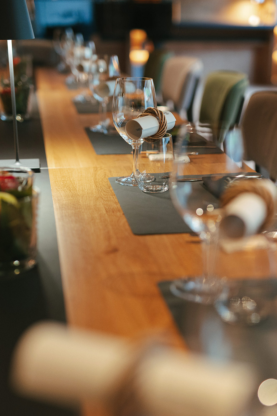 Detailaufnahme eines stilvoll gedeckten Community Tables mit Gläsern und Platzkarten in warmem Licht